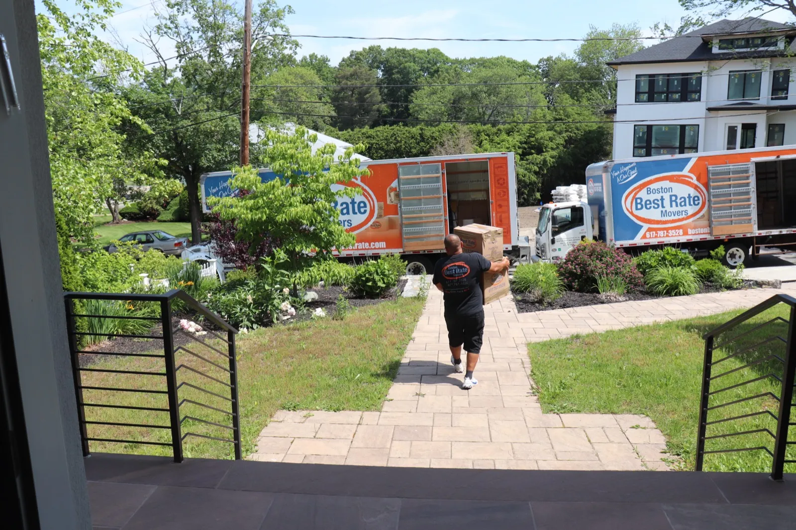 Boston Best Rate Movers crew member carrying boxes from truck to house